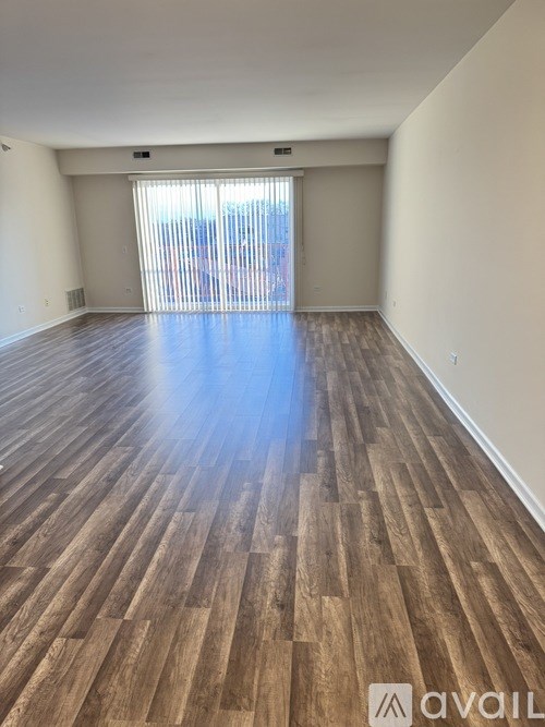 A room with wooden flooring and a window with blinds.
