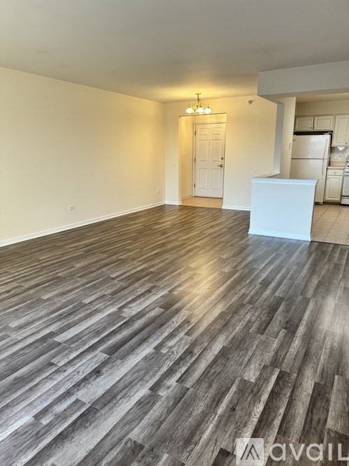 A room with wooden flooring and a white kitchen area.