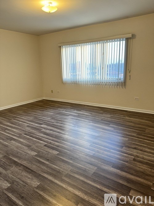 A room with wooden flooring and a window with blinds.