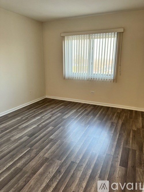 A room with wooden flooring and a window with blinds.