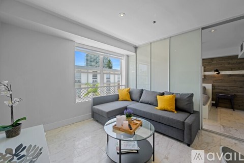 A modern living room with a grey sofa and a glass table.