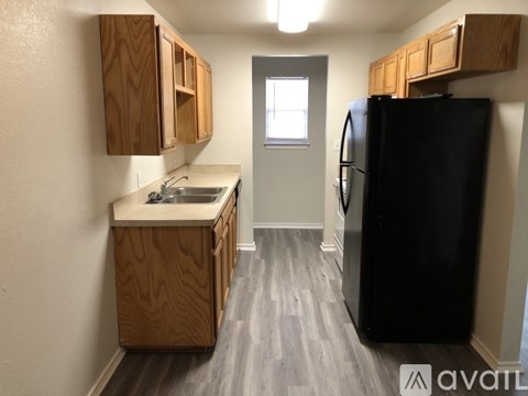 A kitchen with a black fridge and wooden cabinets.
