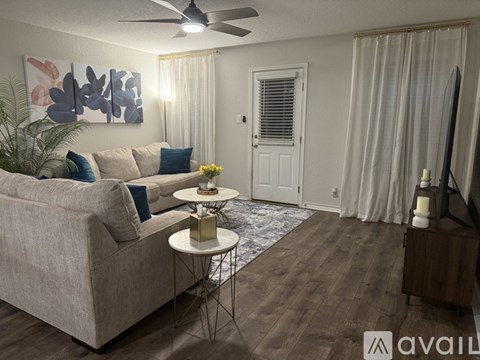 A living room with a beige couch, a ceiling fan, and a painting on the wall.