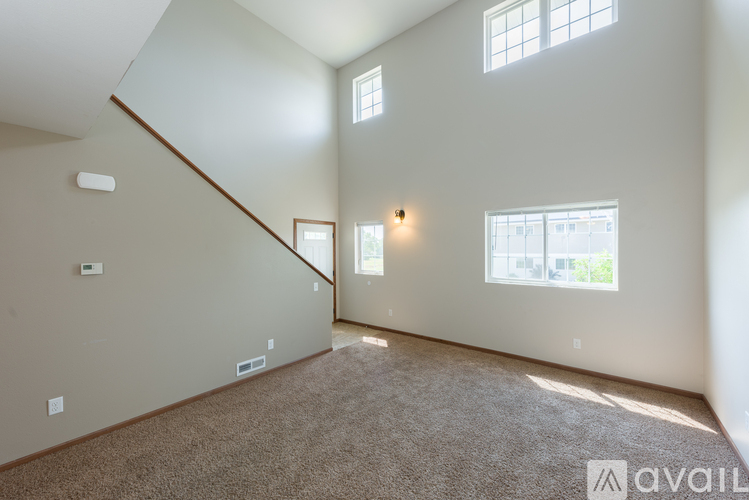 A spacious room with a carpeted floor and two windows.