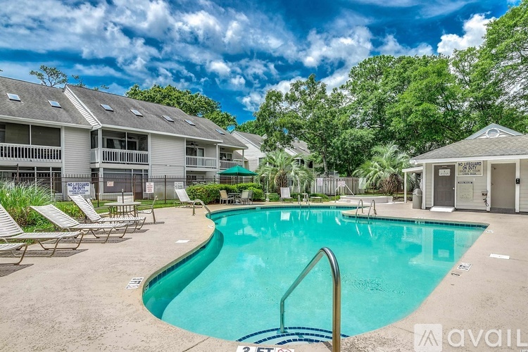 A swimming pool surrounded by lounge chairs and trees.