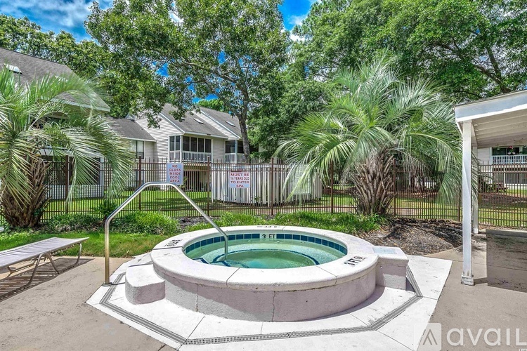 A hot tub is surrounded by a concrete patio and a black fence.