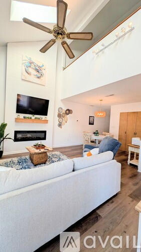A living room with a white couch and a ceiling fan.