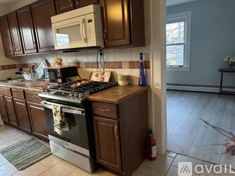 A kitchen with a stove and oven, wooden cabinets, and a window.