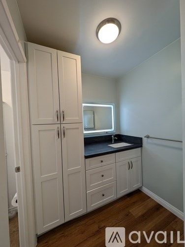 A kitchen with white cabinets and a black countertop.