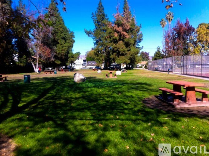 A park with a grassy area, trees, and picnic tables.