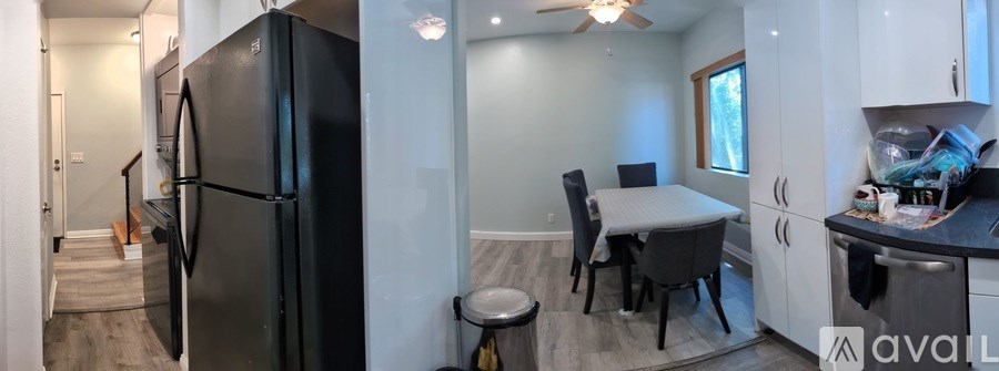 A kitchen with a black fridge and a dining table with chairs.