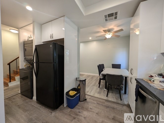 A kitchen with a black fridge and a dining table with chairs.