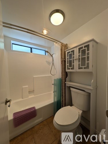 A small bathroom with a toilet, a bathtub, and a cabinet.