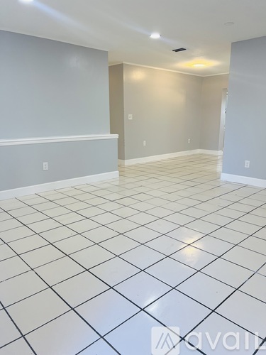 A spacious room with white tiled flooring and walls.