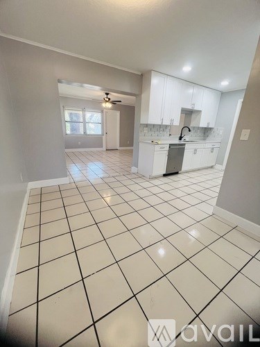A kitchen with white cabinets and a black and white tiled floor.