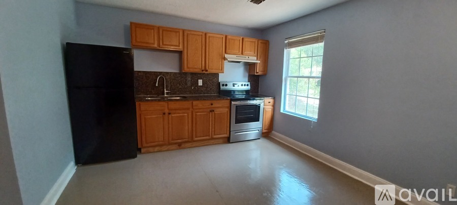 A kitchen with wooden cabinets and a black refrigerator.