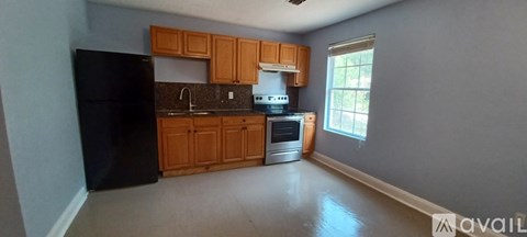 A kitchen with wooden cabinets and a black refrigerator.