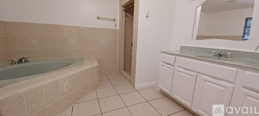 A bathroom with a tub, sink and mirror.