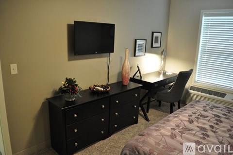 A black dresser with a flat screen TV mounted above it in a bedroom.