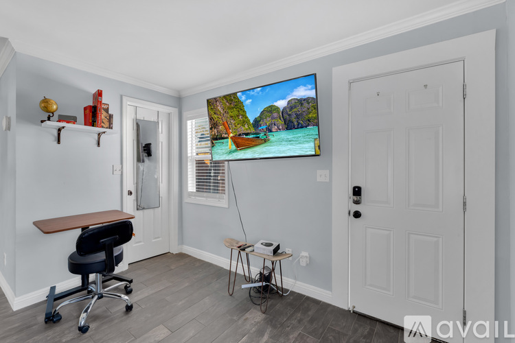A room with a television on the wall and a chair in front of it.
