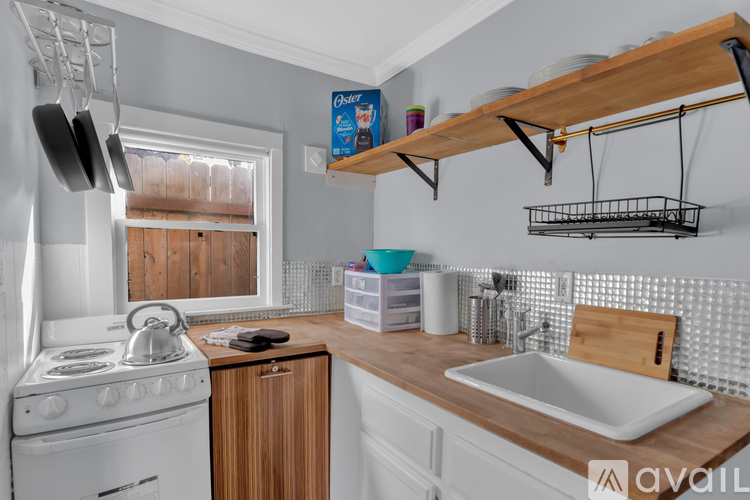 A kitchen with a white stove, wooden cabinets, and a white sink.
