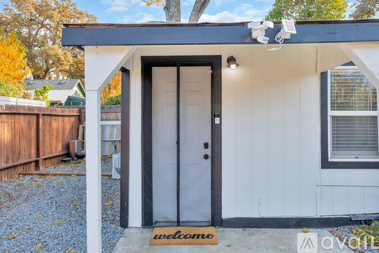 A small white house with a black door and a welcome mat.