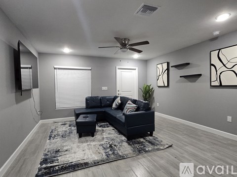 A living room with a black couch and a rug.