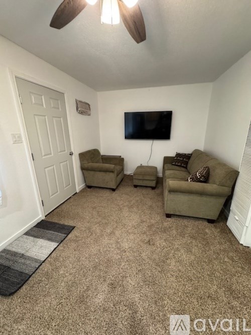 A living room with a flat screen TV mounted on the wall and two couches.