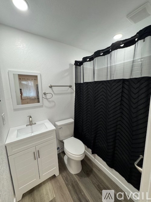 A bathroom with a white sink, toilet, and a black and white shower curtain.