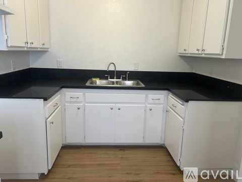 A kitchen with white cabinets and black countertops.