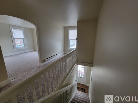 A white staircase with a railing and a window overlooking a building.
