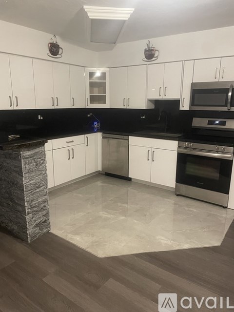 A kitchen with white cabinets and a stone island.