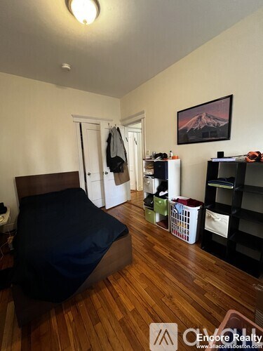A bedroom with a bed, a bookshelf, and a painting of a mountain.