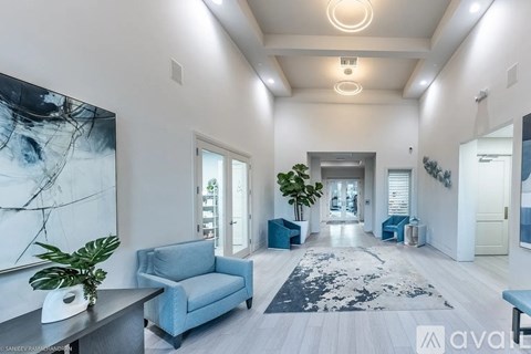 A spacious living room with a blue couch and a large abstract painting on the wall.