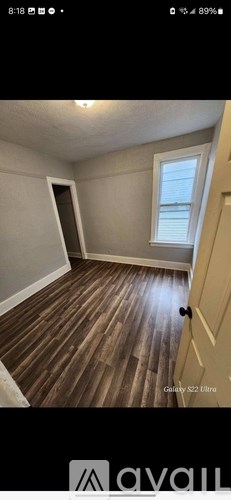 A room with wooden flooring and a door leading to a hallway.