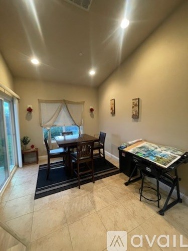 A dining room with a table and chairs and a painting on the wall.