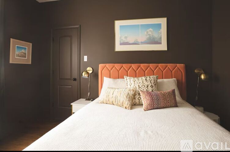 A bedroom with a large bed and a painting on the wall.