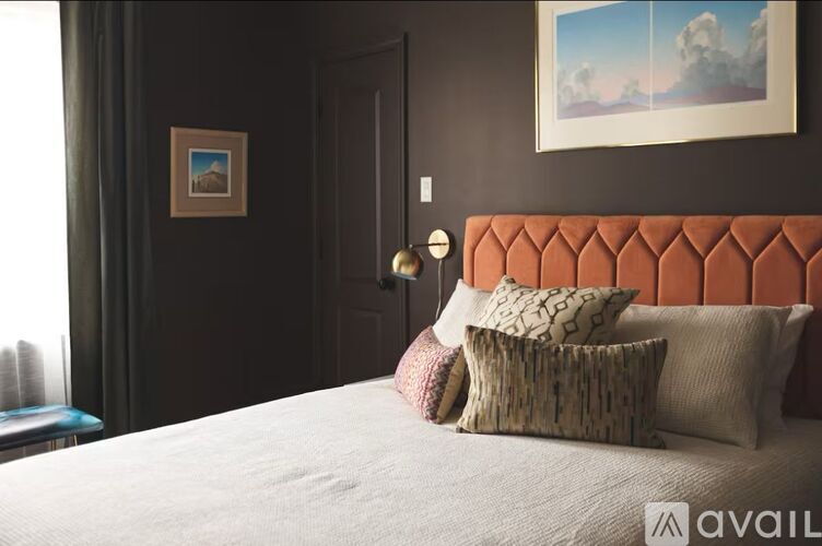 A bed with a white comforter and four pillows with different patterns and designs.