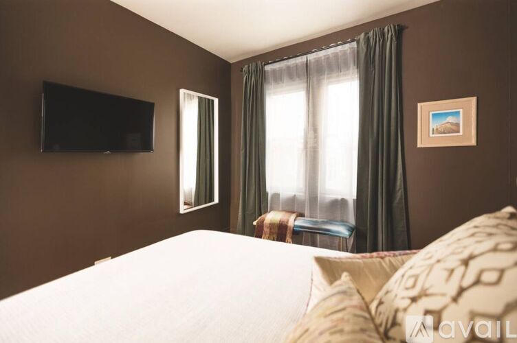 A bedroom with a bed, a television, and a window with curtains.