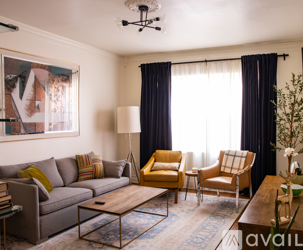A living room with a grey couch, a yellow chair, a wooden coffee table, and a painting on the wall.