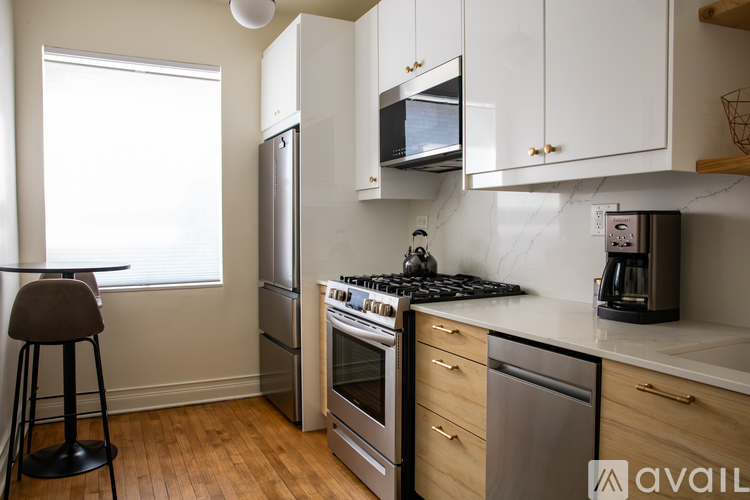 A kitchen with a stove top oven, refrigerator, microwave, and a coffee maker.