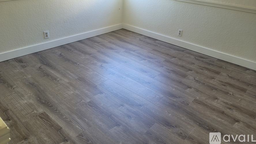 A room with wooden flooring and white walls.