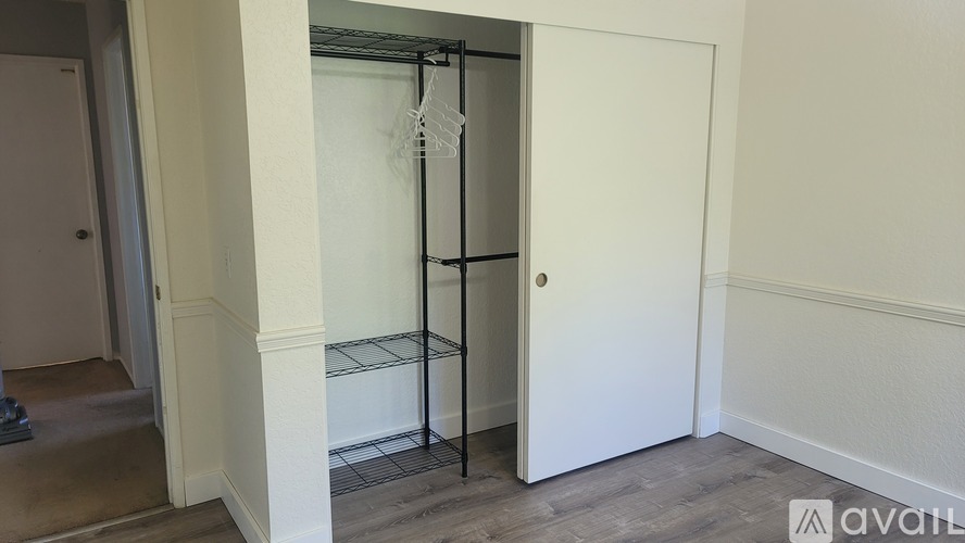 A white door is open to a hallway with a black shelf.