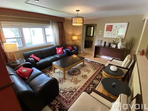 A living room with a black leather couch and a rug.