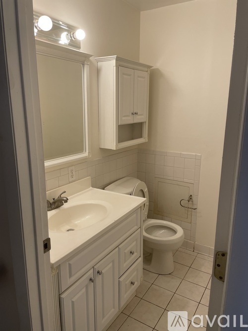 A bathroom with a toilet, sink, and mirror.