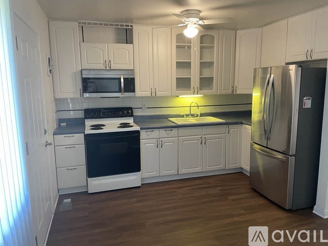 A kitchen with white cabinets and a stainless steel refrigerator.