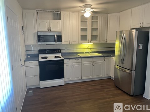 A kitchen with white cabinets and a stainless steel refrigerator.