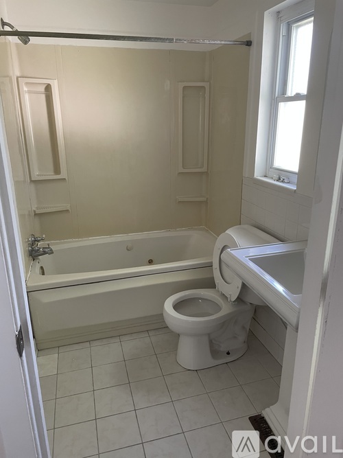 A white bathroom with a toilet, sink, and bathtub.