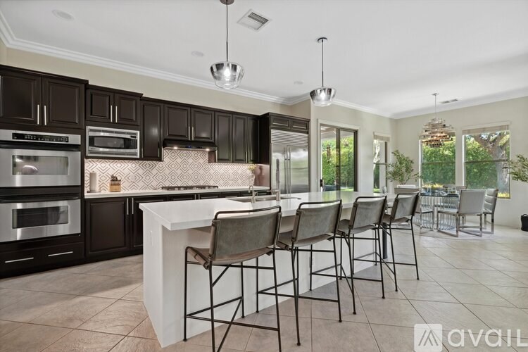 A kitchen with a white island and black cabinets.