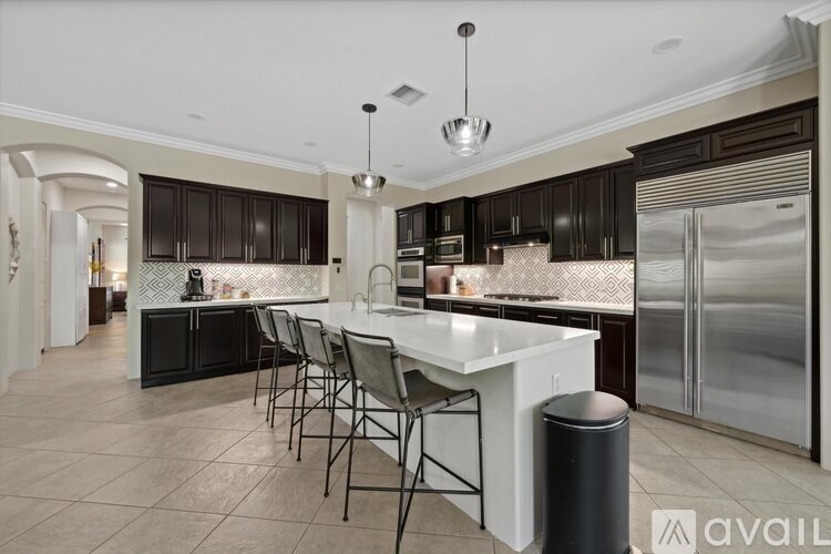 A kitchen with a white island and black cabinets.